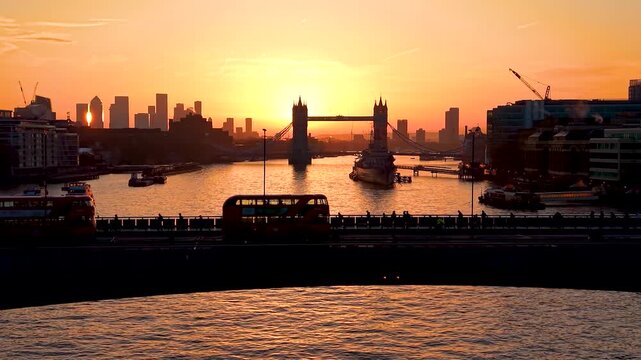 Aerial view of London Bridge during sunrise morning rush hour with street traffic and commuters going into the City offices, the famous Tower Bridge in the background