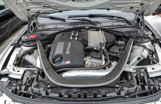 The high performance engine bay of a BMW M model reveals an S55 twin turbocharged powerplant enhanced by carbon fiber bracing and aftermarket RKTunes intake components