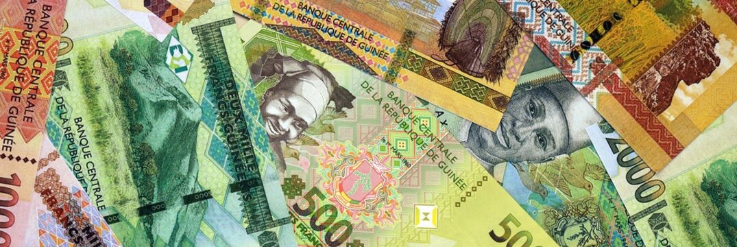 Guinean franc money bills in pile on table. Guinea GNF currency cash close up
