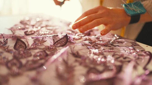 Designer's hands cutting purple sequin fabric