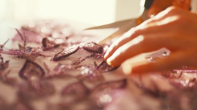 Seamstress cutting embellished lace fabric with scissors