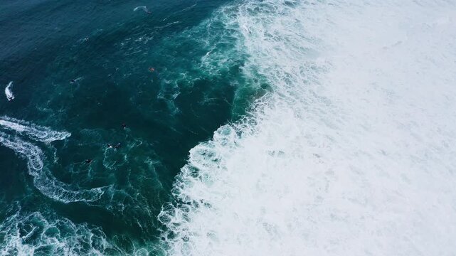 Powerful jet ski personal watercraft navigating massive Atlantic Ocean waves during a professional surfing challenge near Farol da Nazare, Portugal, home of the world record highest surf. 4K