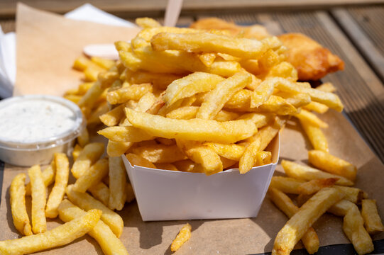 Fish and chips on Le Treport promenade &mdash; golden battered cod with mountain of french fries, seaside flavors enjoyed outdoors by the harbor in Normandy, France