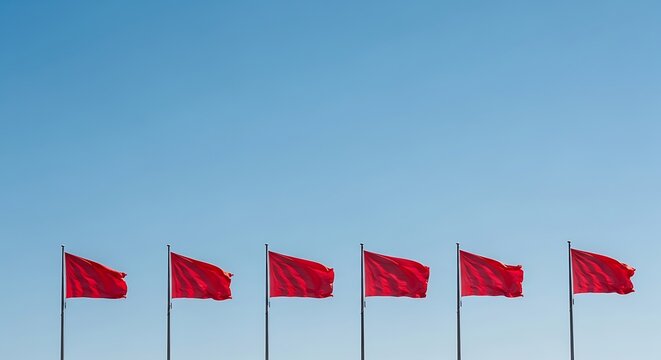 Six red flags waving in a row against a clear blue sky