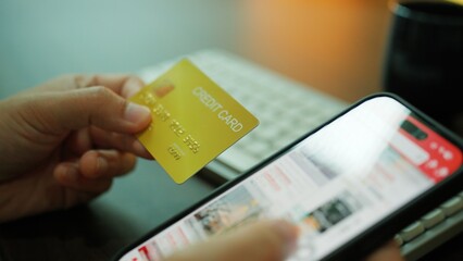 Closeup of a person holding a credit card while shopping online on a smartphone, representing...