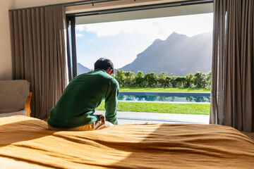 Naklejka premium Mustard duvet is covering bed in bedroom while sliding glass door is revealing pool and mountains