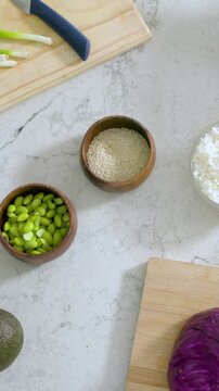 Vertical video: Sliding camera revealing prep area on marble counter, revealing edamame and cabbage