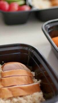 Vertical video: Panning camera showing black box on white table with grain meat and veg for meals