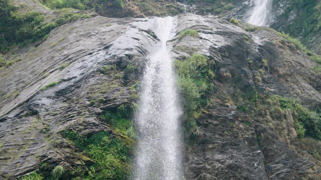 Low angle view of waterfall cascading down a steep rocky cliff in mountains