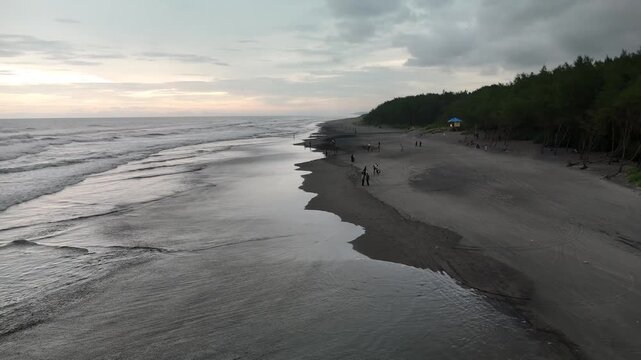 Drone Following Along Pantai Cemara Beach Coastline at Sunset in West Java Indonesia