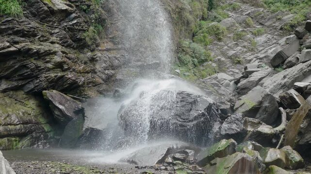 Close up view of fresh water waterfall cascading over mossy rocks in forest