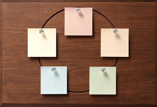 Five Square Sticky Notes Pinned on a Wooden Board in a Circle Arrangement