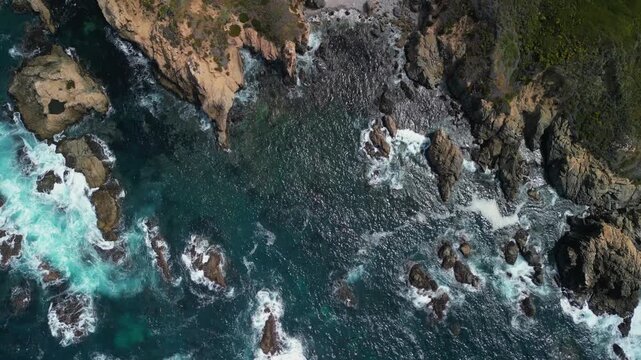 Aerial drone footage of the dramatic coastline at Point Lobos in Big Sur, California. The shot captures rugged cliffs, turquoise Pacific Ocean waves, rocky coves, and untouched natural landscapes.

