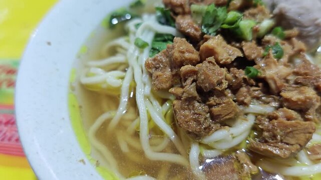 Close up of chicken noodles or mie ayam served in a bowl and still hot, steaming