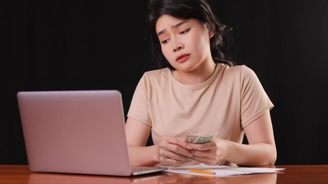 Asina woman counting her money while trying to pay her bills.