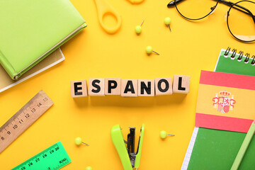 Obraz premium Espanol word blocks with spanish flag and school supplies on yellow background for language learning