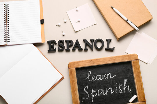 Spanish language learning with "espanol" letters, chalkboard, notebooks, and pen on neutral background