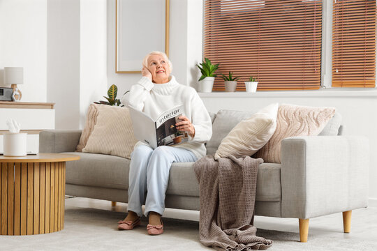 Senior woman with magazine on sofa suffering from loud neighbours at home