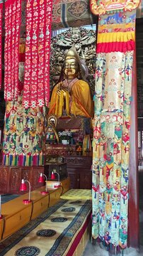 Beijing, China - May 10, 2026: Yunhegong Tibetan Buddhist Temple, Lamaist Temple. Tibetan Buddhist temple interior with colorful prayer flags, ornate decorations, and a large golden statue of a Buddha