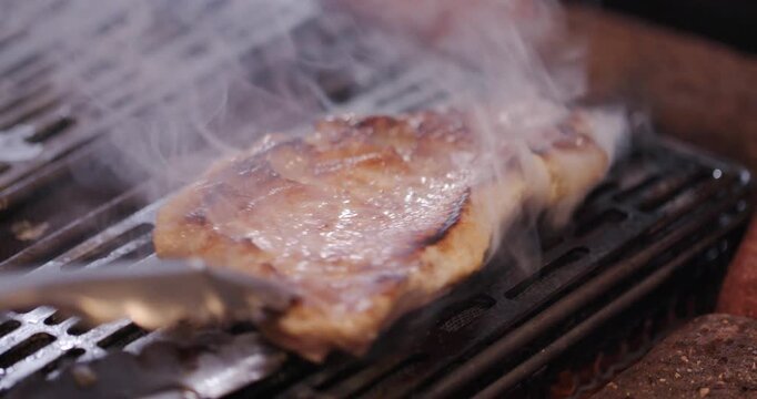 炭火の炎でこんがり焼き色がつく豚肉のアップ映像