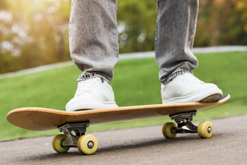 Legs of young man with skateboard in park, closeup © Pixel-Shot