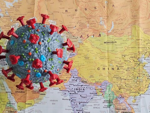 COVID-19 virus model placed on a world map showing Asia
