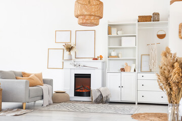 Obraz premium Interior of living room with grey sofa, coffee table, shelving units and autumn home decor on fireplace near white wall