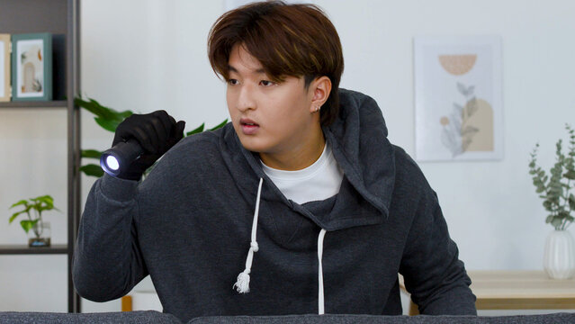 Young Asian Man in Hoodie Holding Flashlight in Living Room