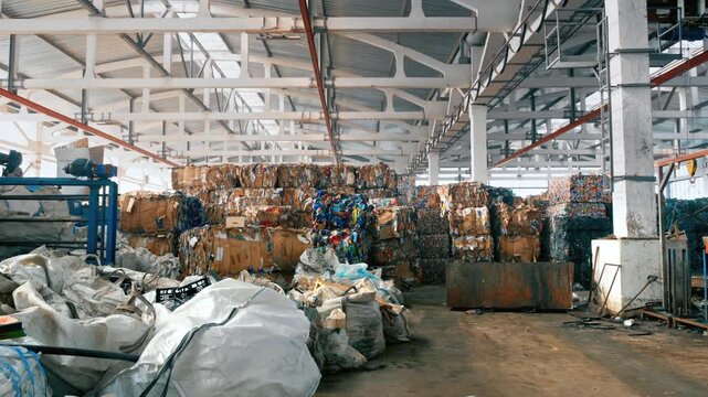 A large industrial warehouse storing sorted pressed waste paper and plastic bales for recycling.