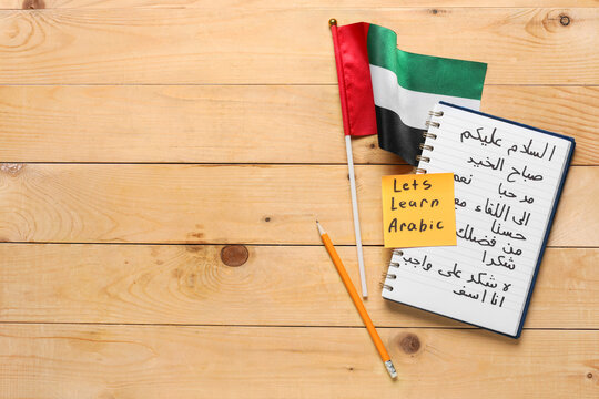 Arabic language learning with UAE flag, notebook, pencil, and "lets learn arabic" note on wooden background