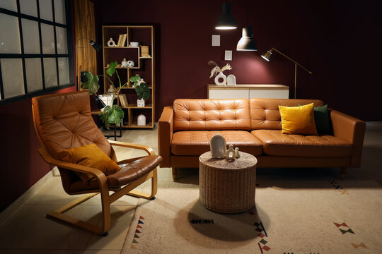 Cozy living room interior with brown leather sofa, armchair, and modern decor elements