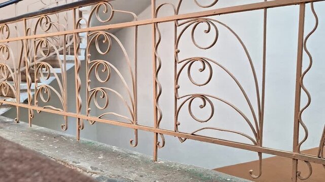 Elegant wrought iron staircase railing along a building landing, highlighting intricate metalwork, decorative details, safety features, durable construction, classic craftsmanship, and timeless style