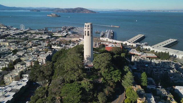Aerial drone footage of Coit Tower in San Francisco, California, captured from above with stunning panoramic views of the city skyline, Telegraph Hill, the San Francisco Bay, and surrounding urban lan