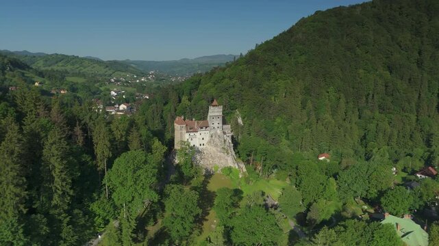 Stunning high altitude reverse panoramic orbit over magnificent Bran Castle and surrounding Transylvanian countryside in early summer, cinematic drone reveal