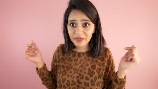 Portrait of a shocked confused young Indian woman looking at camera feels amazed isolated against pink colour studio background.