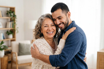 Fototapeta premium Smiling senior woman embracing a young man in a living room