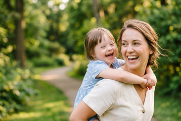 Fototapeta premium Woman giving piggyback ride to daughter in outdoor park