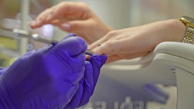 Close-up manicure treatment with nail technician filing and shaping a client&rsquo;s fingernail