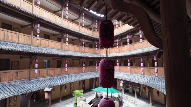 Wangxian Valley, China, 04 April 2026 ? Interior courtyard of a circular Tulou-style wooden building adorned with rows of pink Chinese lanterns hanging across multi-story balconies in spring.