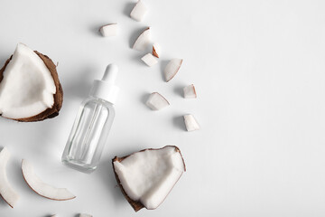 Obraz premium Bottle of coconut cosmetic oil and cut fruit on grey background