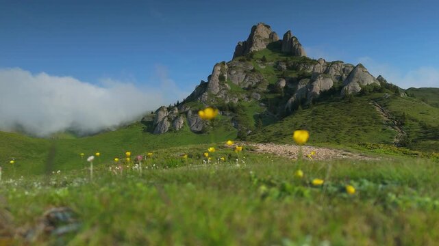 Picturesque rocky peak of Tigaile Mari with cascading clouds in the tranquil Ciucas Mountains, ground level static shot, 4K