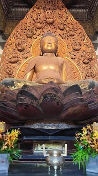 Vertical tilting shot of a Buddha statue inside Byodo-In Temple