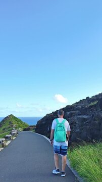 Tourist hiking along the scenic Makapuu Point cliffside pathway