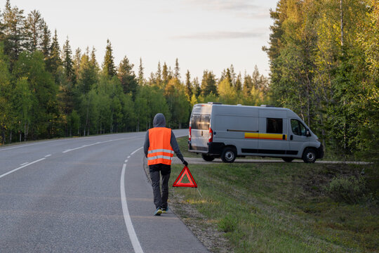 Person with warning triangle and broken down van