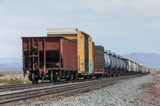 Long freight train travels through a desert landscape