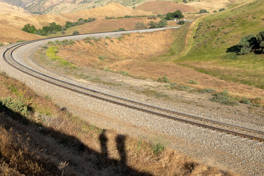 Curved train tracks winding through grassy hills