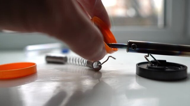 A soldering iron for repairing gadgets. A worker repairs devices with a soldering iron