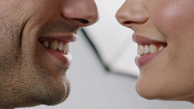 Extreme close-up shot of two pairs of lips facing each other in perfect side profile, man's lips on the left side of frame and woman's lips on the right side of frame, both facing each other