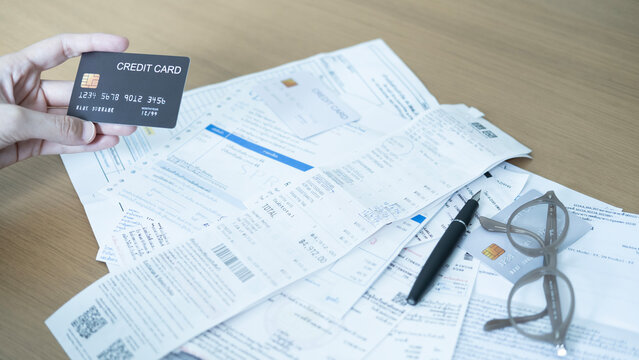 Credit card on financial documents with receipts, pen and glasses, showing monthly bills, household expenses and credit card spending.