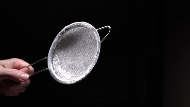 Metal sieve for sifting flour on a black background